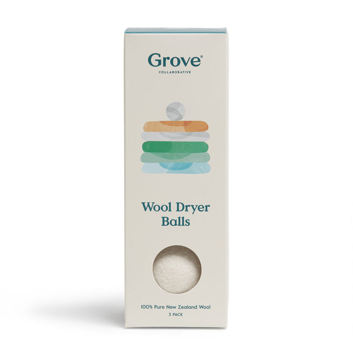 A box of Grove Collaborative Wool Dryer Balls made from 100% pure New Zealand wool. The packaging is off-white with colorful folded towel graphics and a small circular window showing the white dryer balls inside.