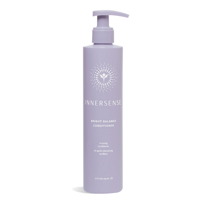 A tall, lavender bottle of Innersense Bright Balance Conditioner with a pump dispenser. The bottle features a white sunburst design and product information in white text.