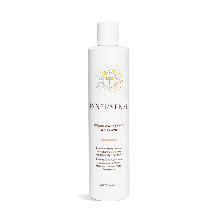 A white bottle of Innersense Color Awakening Hairbath shampoo with gold and black text and a circular, sun-inspired design on the label. The bottle stands upright on a white background.