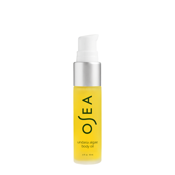 A clear bottle of Osea Undaria Algae Body Oil with a silver pump cap, filled with yellow oil, and the product name printed vertically on the front.