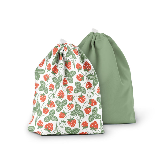 Two drawstring bags: one with a red and green strawberry pattern and white background, and the other in solid sage green. Both bags are standing upright against a white background.