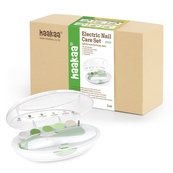 An electric nail care set with a pale green and white trimmer, multiple attachments, and a clear case, shown in front of its brown and green haakaa-branded packaging box.