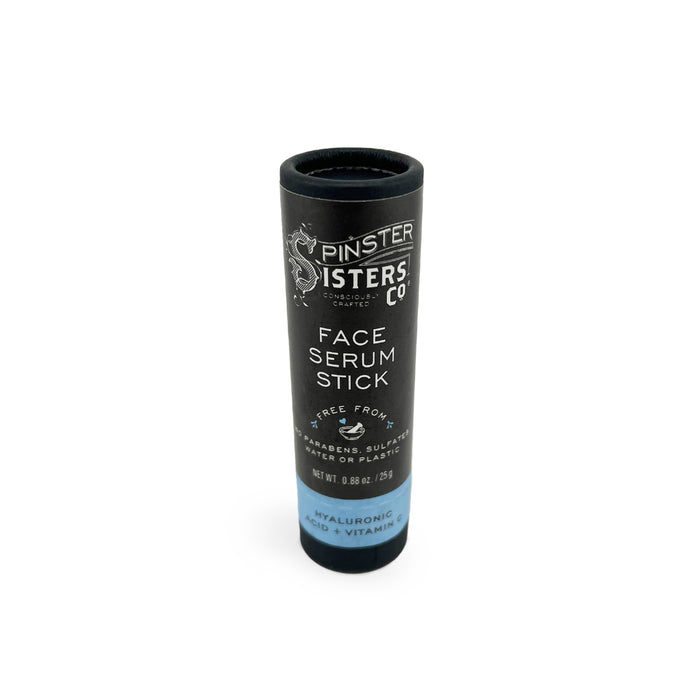 A black cylindrical tube labeled Spinster Sisters Co. Face Serum Stick with details about being free from parabens, sulfates, and plastic. The bottom mentions Hyaluronic Acid + Vitamin C.