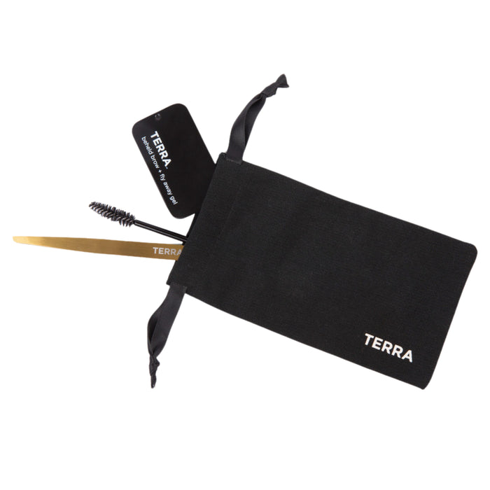 A black pouch labeled TERRA with a gold metal eyebrow tool, a spoolie brush, and a black product tag partially out of the pouch against a white background.