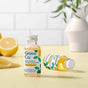 Two bottles of Grove Co. multi-purpose cleaner concentrate (lemon & eucalyptus) on a yellow surface, with one bottle upright and one lying down. Sliced lemons and green leaves are in the background.