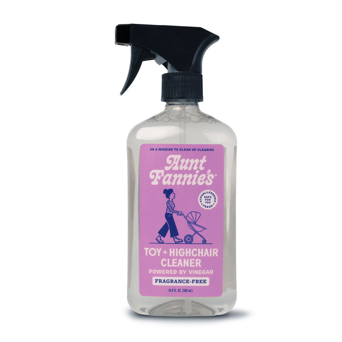 A spray bottle of Aunt Fannie’s Toy + Highchair Cleaner with a black nozzle, clear liquid, and a purple label featuring a woman pushing a stroller. The cleaner is fragrance-free and powered by vinegar.