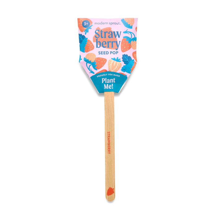 A wooden stick labeled STRAWBERRY holds a colorful paper top with strawberries and leaves. The top reads modern sprout. Strawberry SEED POP. Plant Me! indicating it’s a plantable seed pop for growing strawberries.