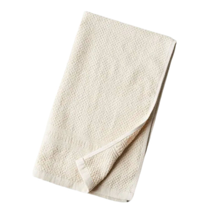 A folded, off-white bath towel with a textured surface is shown on a white background. One corner of the towel is slightly turned up, revealing the inside.