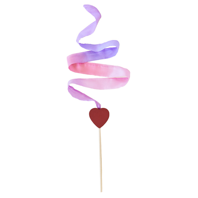 The Heart Streamer by Sarahs Silks features a red heart-shaped cutout on a stick, adorned with pink and purple silk streamers creating a whimsical spiral pattern against a plain white background.