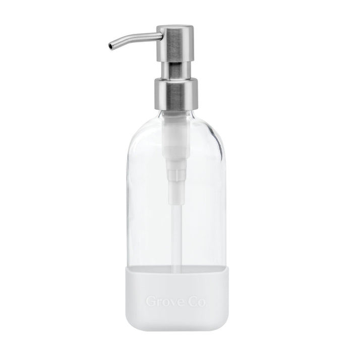 A clear glass soap dispenser with a stainless steel pump and a white silicone sleeve at the base, featuring the words Grove Co. embossed on the sleeve.