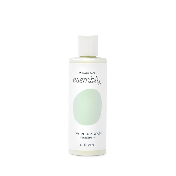 A white bottle of Esembly Wipe Up Wash Concentrate with a green oval design on the label. The bottle contains 8 fl oz (236 mL) of liquid and is labeled as cloth safe.