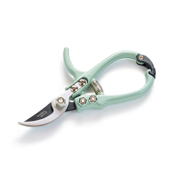 A pair of light green gardening pruners with a curved blade and spring mechanism, shown on a white background.