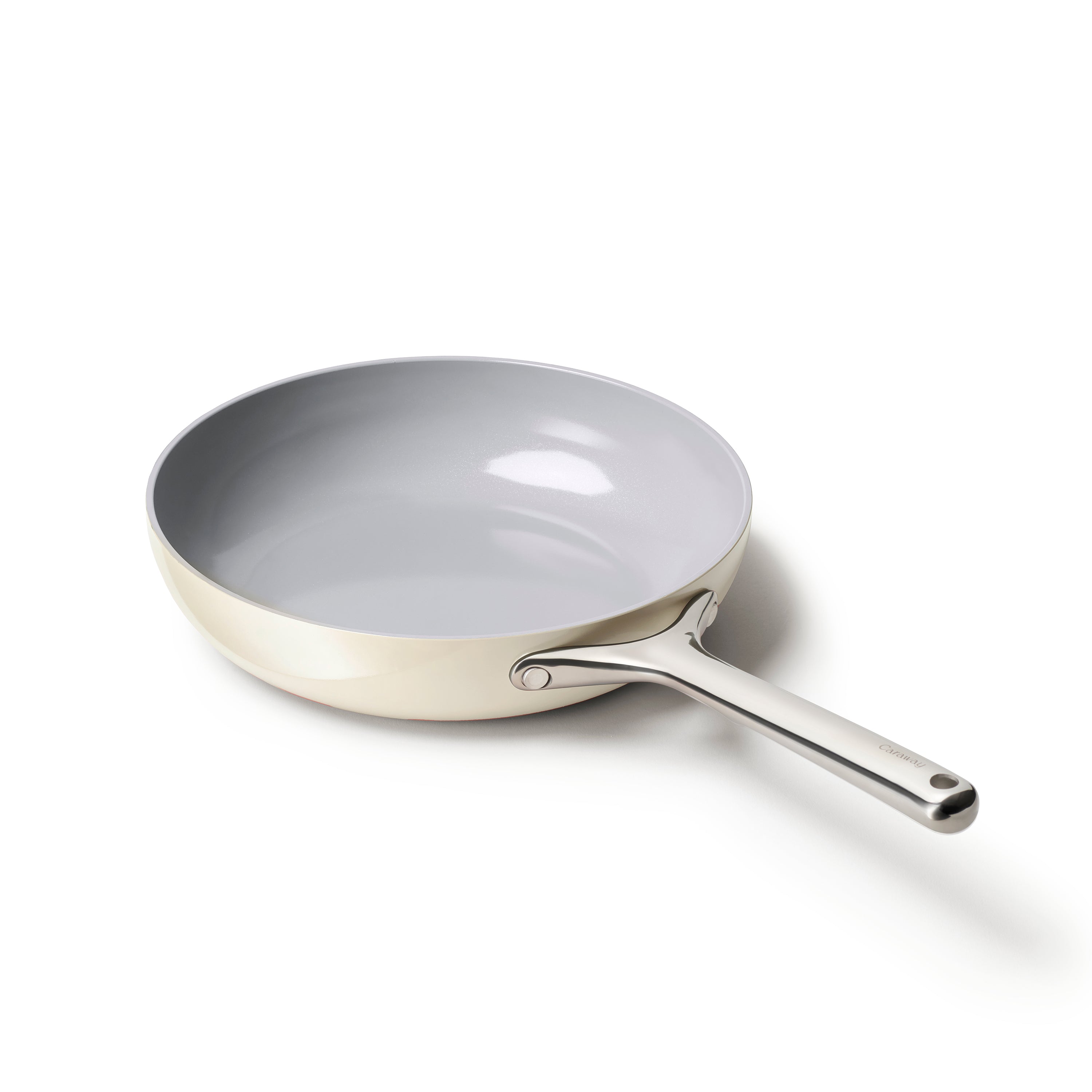 The Caraway Ceramic Fry Pan, 10.5, features a beige ceramic-coated interior with a smooth gray finish for natural non-stick performance. Its long stainless steel handle ensures easy maneuverability, all highlighted against a plain white backdrop.
