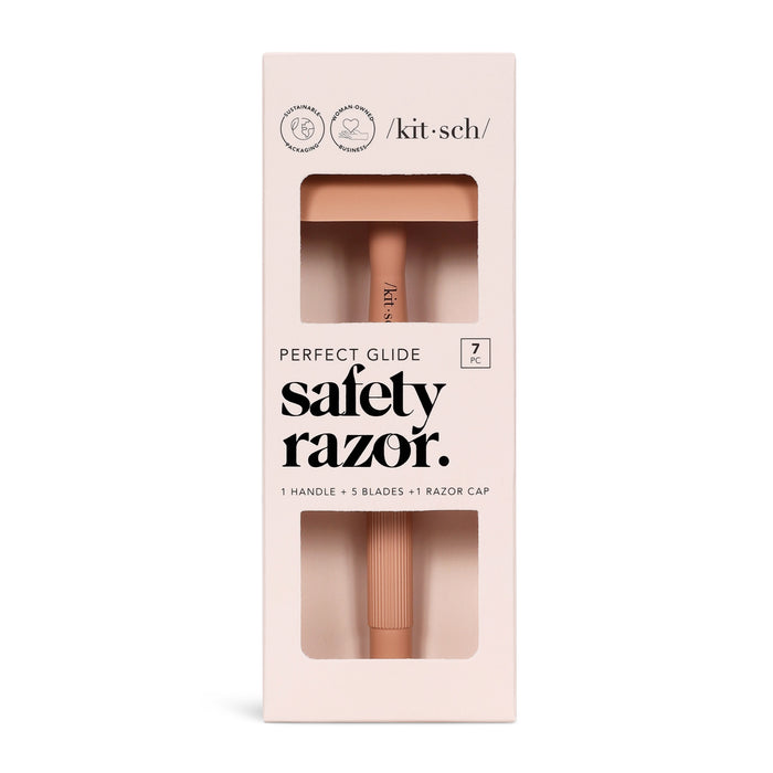 A boxed Kitsch Perfect Glide safety razor set with a pink handle visible through a window. The packaging reads safety razor and includes 1 handle, 5 blades, and 1 razor cap.