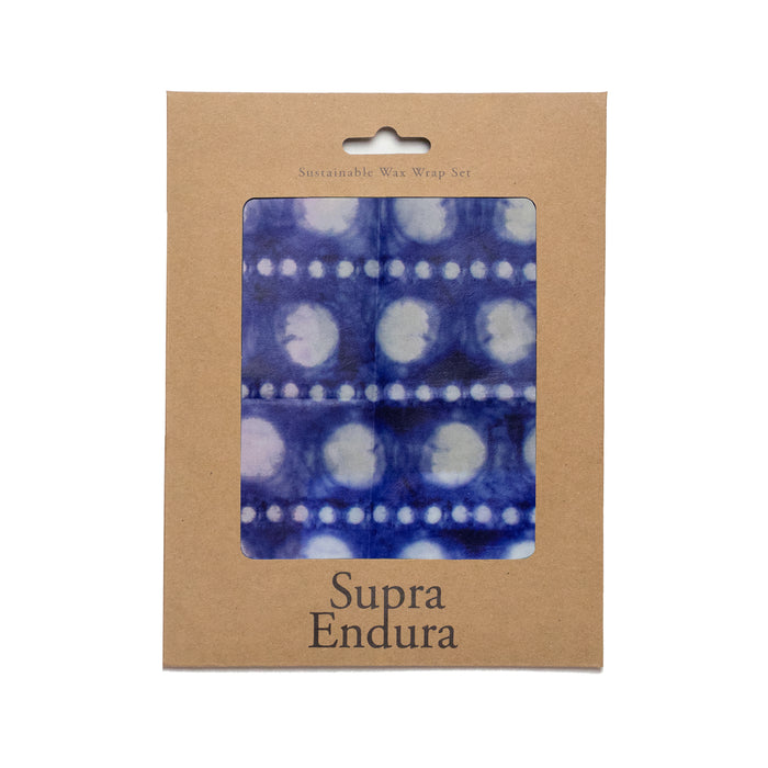 A brown cardboard package labeled Supra Endura contains a blue and white patterned sustainable wax wrap, visible through a clear window in the center.