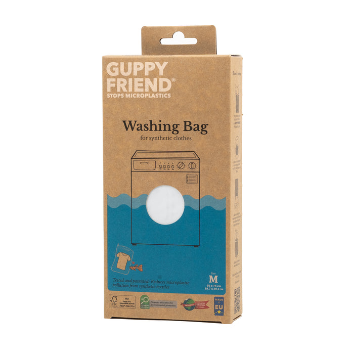 A rectangular cardboard box of Guppyfriend Washing Bag, featuring an illustration of a washing machine and text promoting its use to stop microplastics from synthetic clothes.