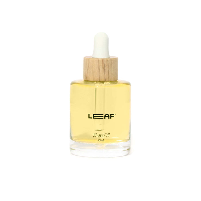 A clear glass bottle of LEAF Shave Oil with yellow liquid inside, a wooden cap, and a white dropper. The label reads LEAF Shave Oil 30ml in black text.