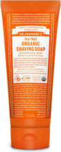 Dr. Bronners Organic Shaving Soap, a 7 oz (207 mL) orange tube, highlights its natural ingredients and benefits with detailed text, boasting organic and fair trade certification. Infused with tea tree essence, it provides a refreshing shaving experience.