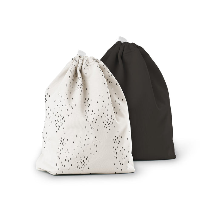 Two drawstring bags are shown. One bag is white with small black dots in a random pattern, while the other bag is solid black. Both bags are standing upright against a white background.