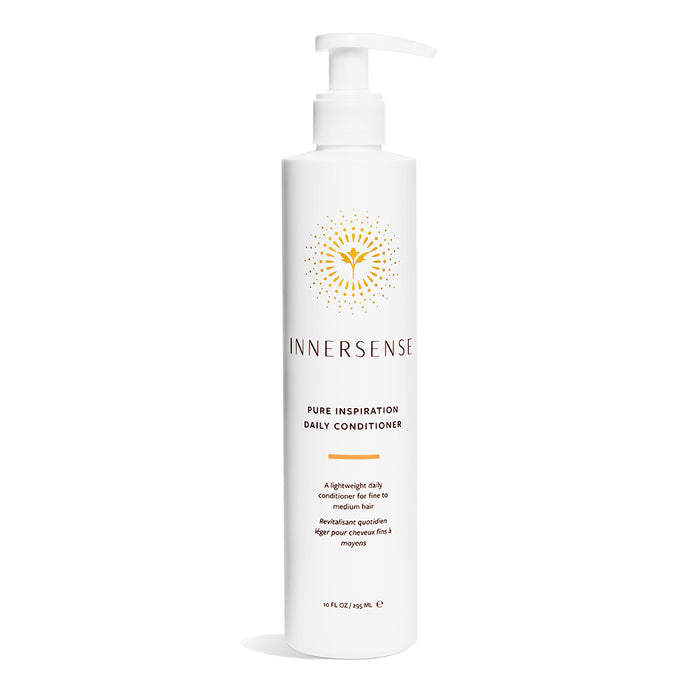 A white bottle of Innersense Pure Inspiration Daily Conditioner with a pump dispenser, featuring a gold sunburst logo and black text on the front, standing upright against a white background.